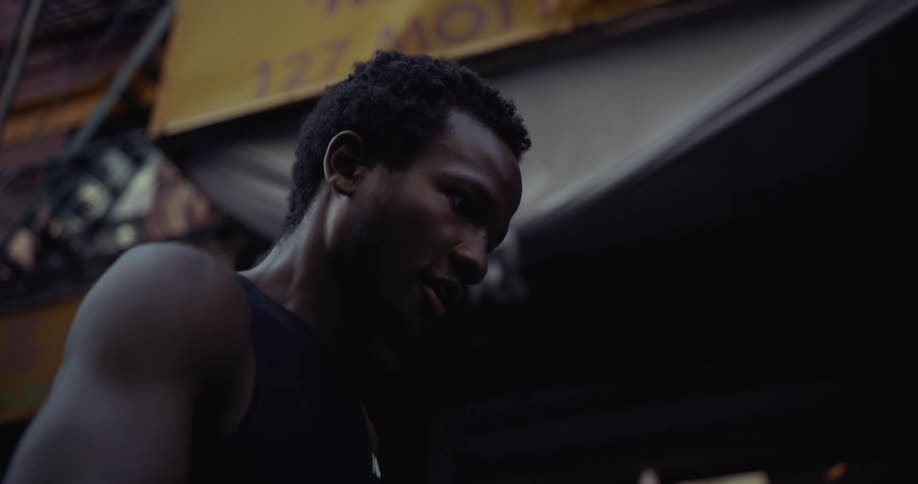 Male runner runs past a busy urban sidewalk during the daytime