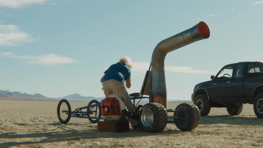 Man adjusting a vehicle with a loud exhaust pipe in a desert area