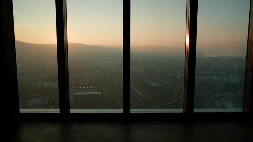 View through a window of a city skyline with the sun rising on the horizon