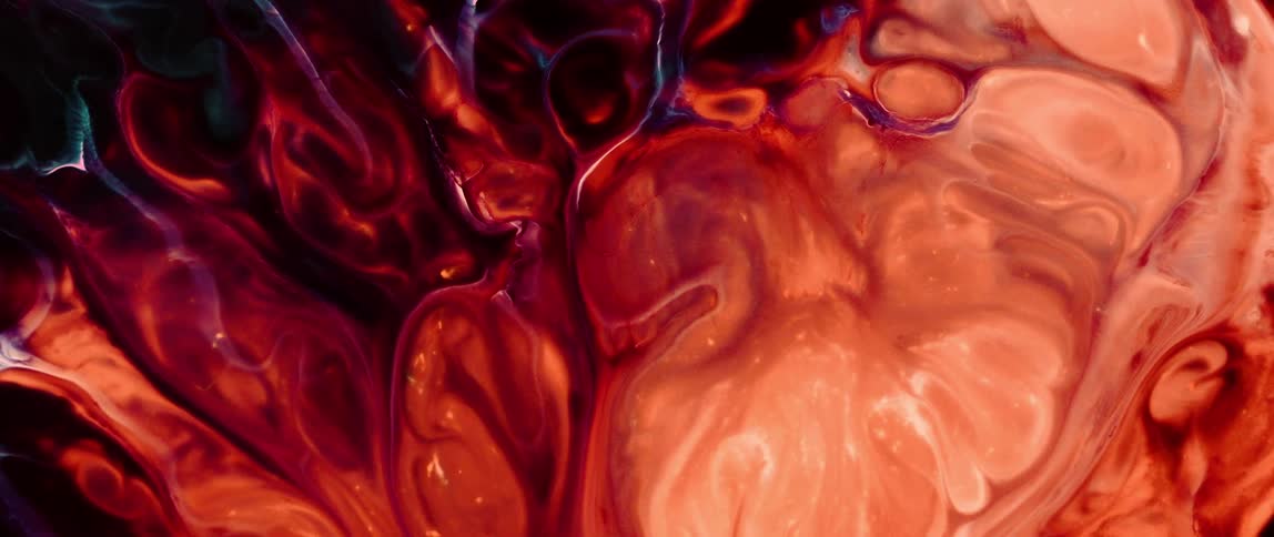 Flowing liquid colors swirl and merge in warm tones of orange red and brown creating an abstract pattern with a hint of dark blue