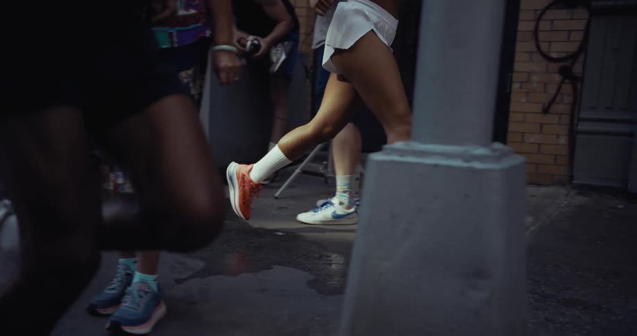 Legs of two runners running among pedestrians on a city street