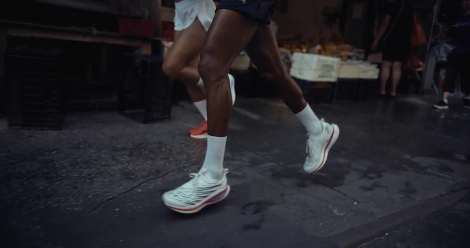 Two people are jogging on a city street near a market area