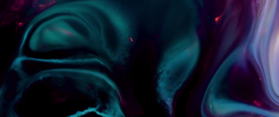 A swirling mass of dark blue and teal liquid with hints of red and white creates an abstract ethereal pattern