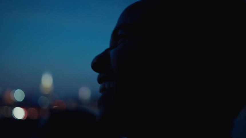 Side portrait of a smiling man outdoors at night