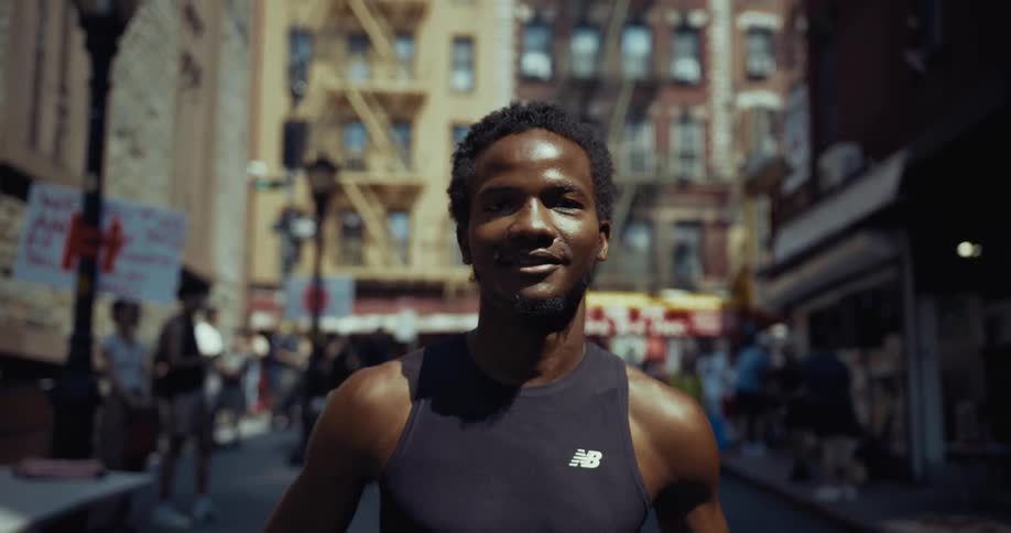 Smiling man doing street jogging with pedestrians watching