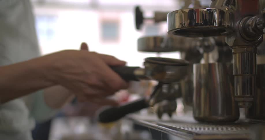 Pair of womans hands operating handles on a coffee machine