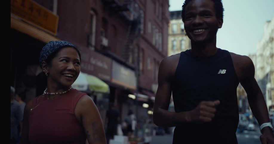 A young couple is jogging on a city street smiling as they go