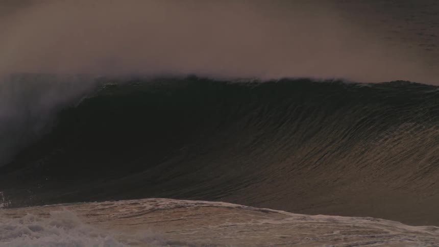 Surfers paddle and ride waves in the ocean