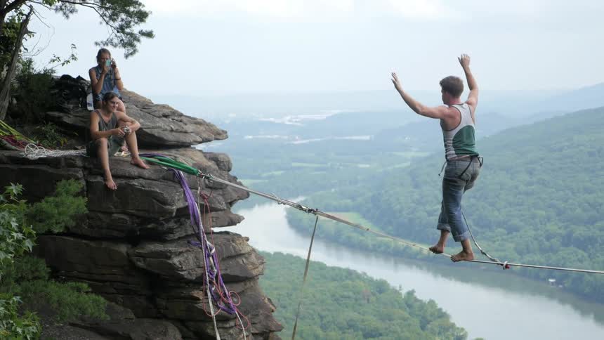 A man balances on a tightrope in a canyon