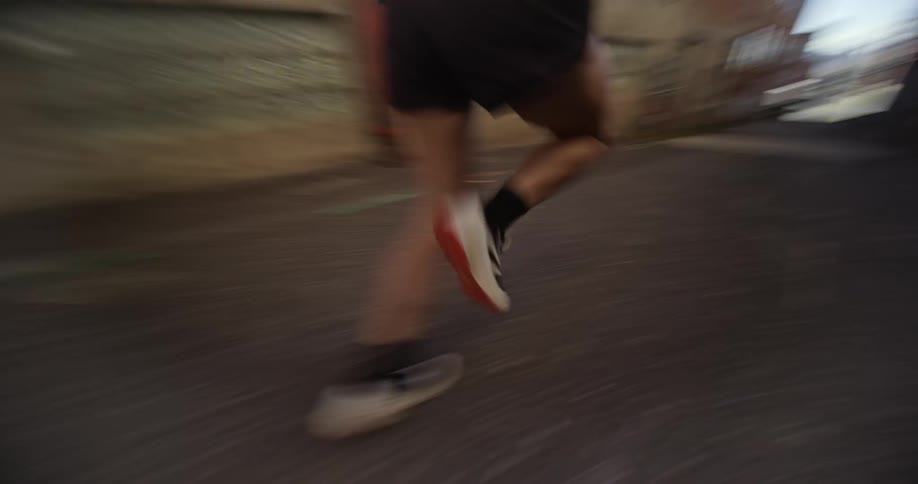 A person is running down a narrow alleyway between two brick buildings