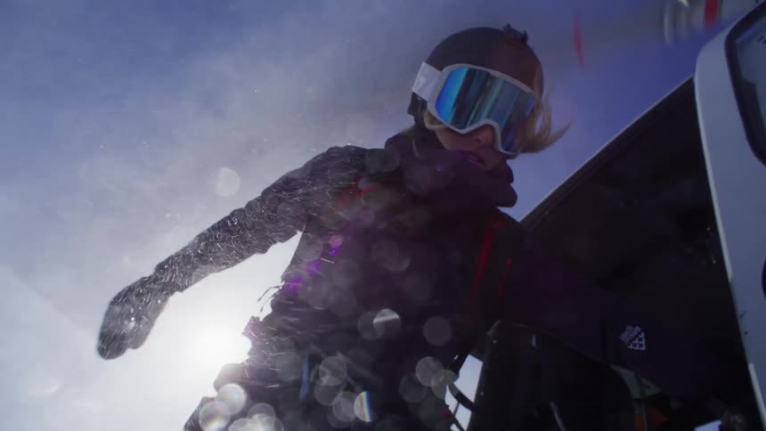 Woman descending from a helicopter wearing ski goggles