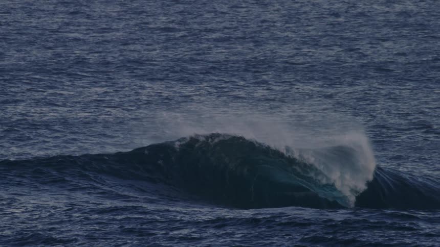 Person bobs on a wave as it breaks during the day