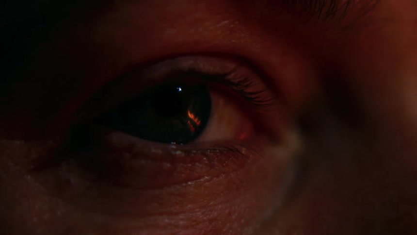 The reflection of a fire can be seen in a womans eye at night