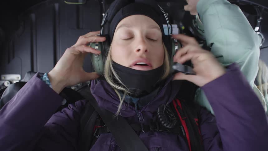 Two women inside a helicopter cabin putting on headphones