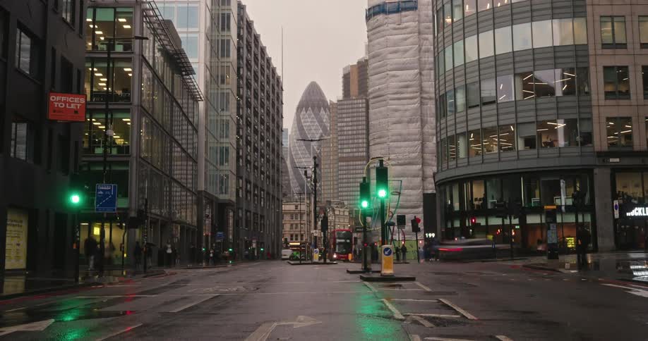 A busy urban street in london with a mix of red doubledecker buses taxis and pedestrians framed by historic and modern buildings
