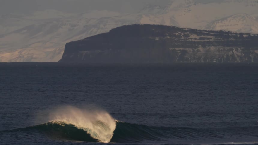 Surfer in an ocean with ice mountains in the background