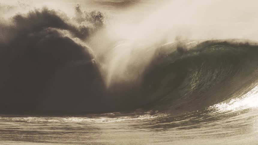 Huge ocean waves are crashing into the water at sunset