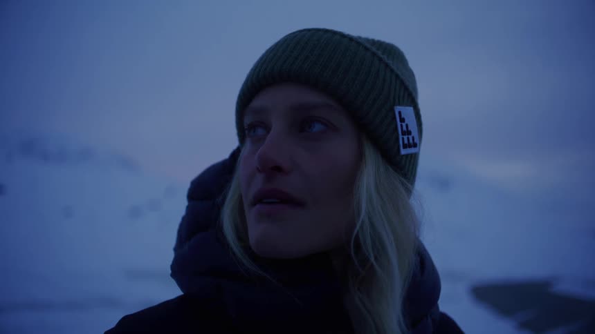 A woman is standing in the snow at sunrise