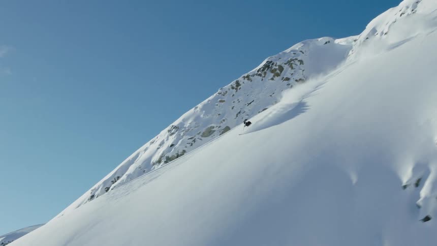 A person is skiing downhill a snow covered mountain
