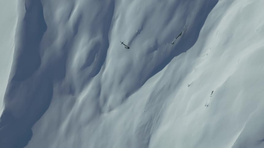 Helicopter is flying above the mountaintops during the winter