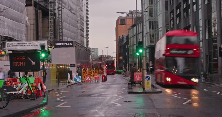 A busy urban street in london with a mix of red doubledecker buses taxis and pedestrians