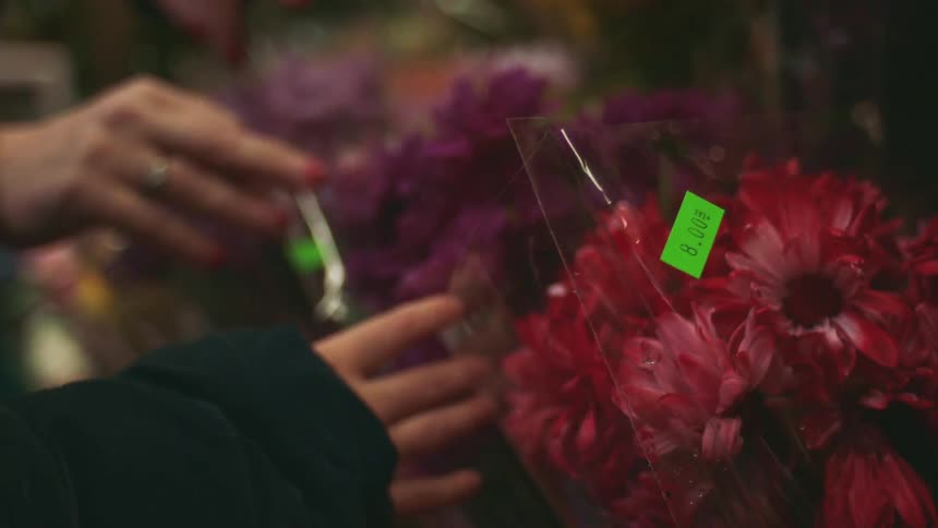 Two people choose bouquets of flowers wrapped in plastic with green price tags