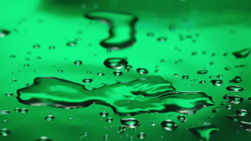 Water drops splash leaving small wet spots on a green surface