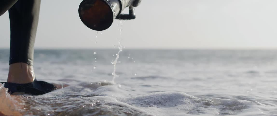 Photographer raises a waterproofed camera from the surf during the daytime