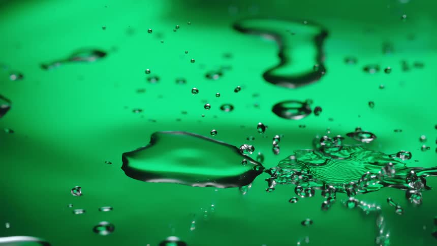 Water drops fall and splash on a green surface