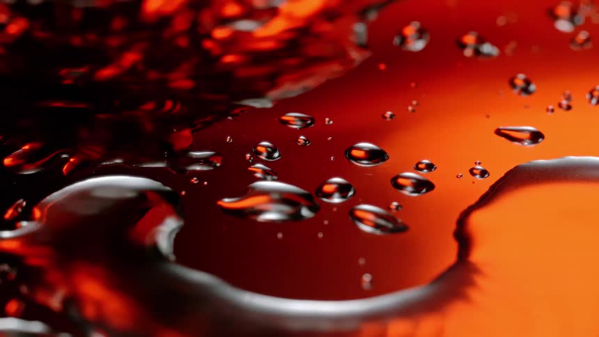 Extreme close up of a water droplet falling on a reflective glass surface