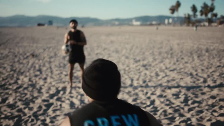 A clip of people playing football by the beach