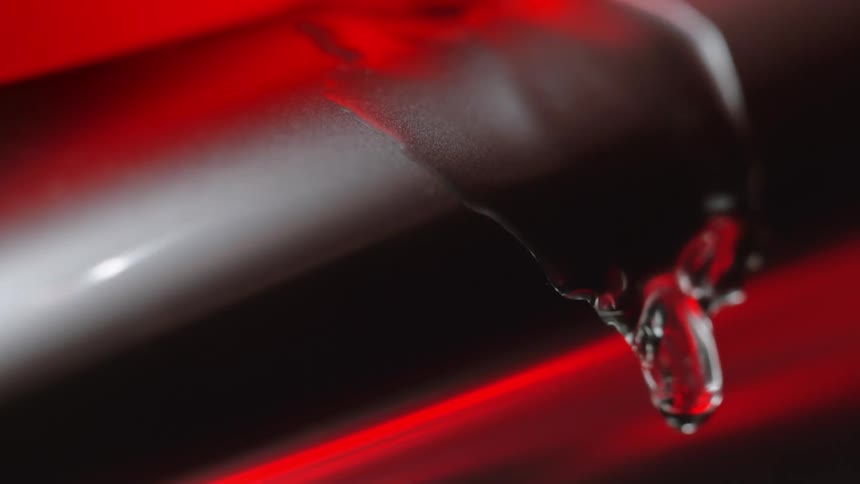 Drops of clear liquid on a brown membrane with orange red ambient lighting