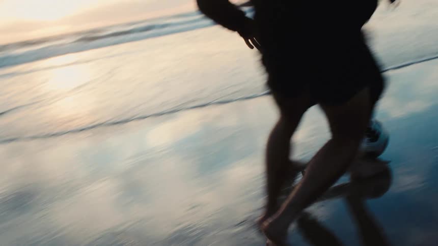 Two people playing soccer on the wet sand of the beach
