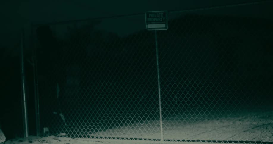 Person opening a metal gate at night
