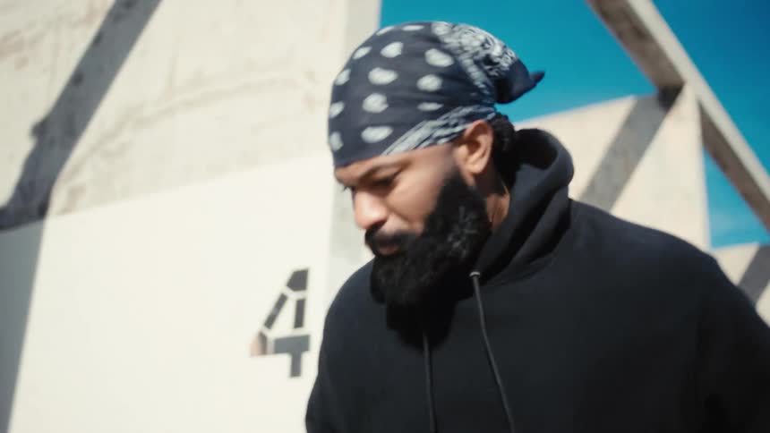 A man with a bandana on his head and he is bouncing a soccer ball on the ground