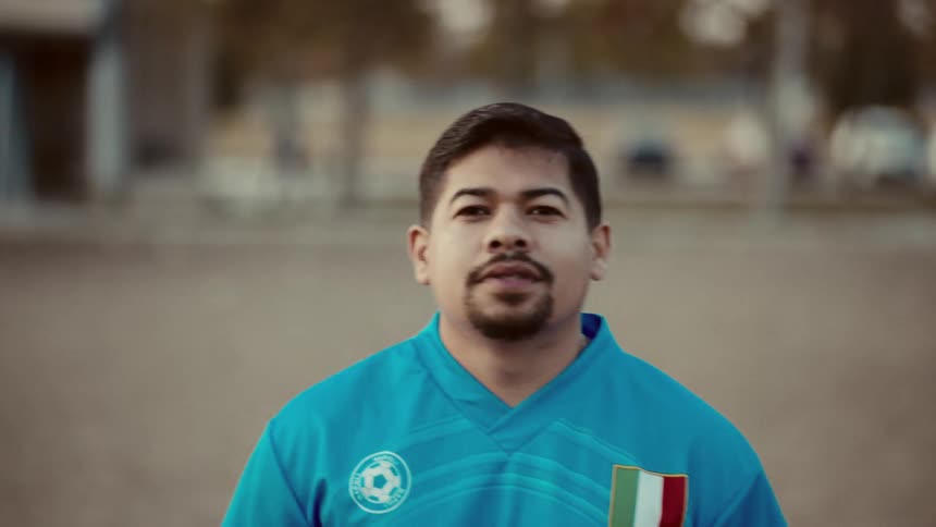 Man running on a sand field wearing a soccer team jersey