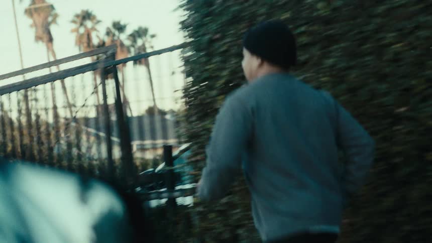 Vehicle paces a man jogging on thesidewalk past a business situated near a residential neighborhood