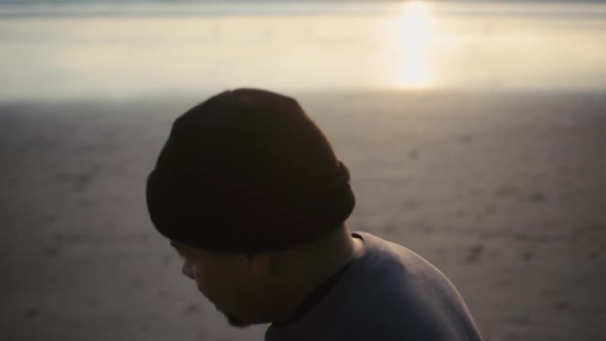 Two male friends kick a soccer ball back and forth while on the beach near sunset