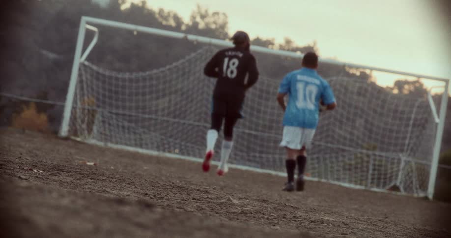 Friends play one on one soccer using a soccer ball and a soccer goal during the autumn