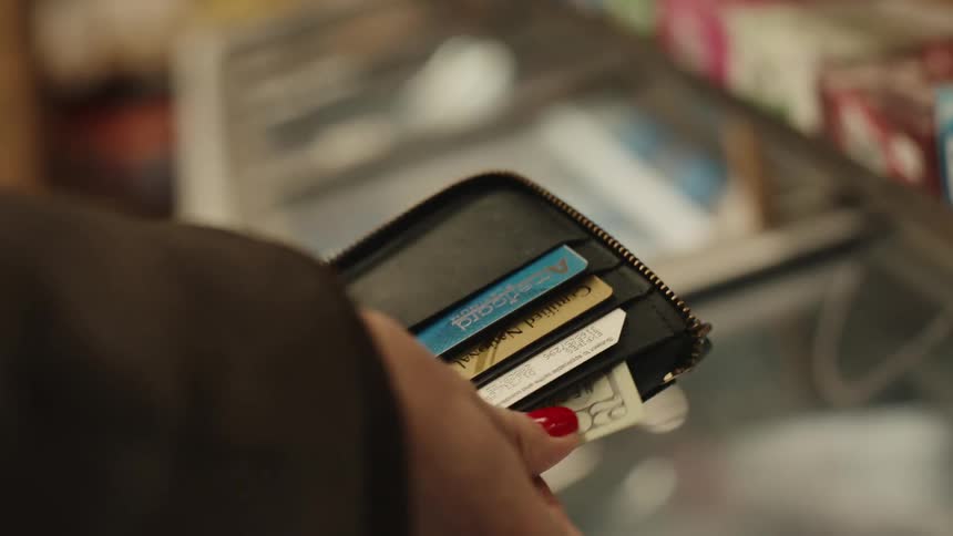 Woman takes cash from her wallet to pay while standing at the counter in a store