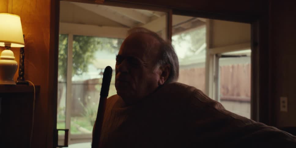 Elderly man with broom dancing in living room
