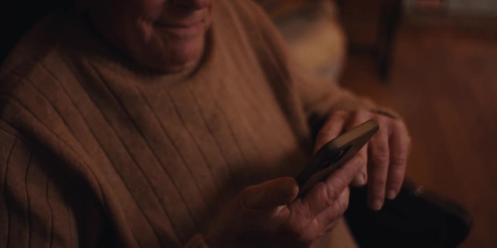 Elderly man reads on his smartphone while sitting at home