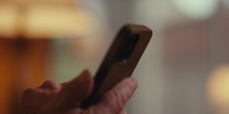 Elderly man smiles while reading on his smartphone