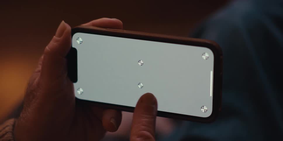 A closeup of a mans hand holding and pointing at a smartphone with a replaceable screen