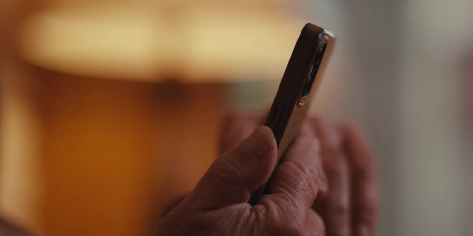 Close up of an elderly mans hands interacting with an iphone