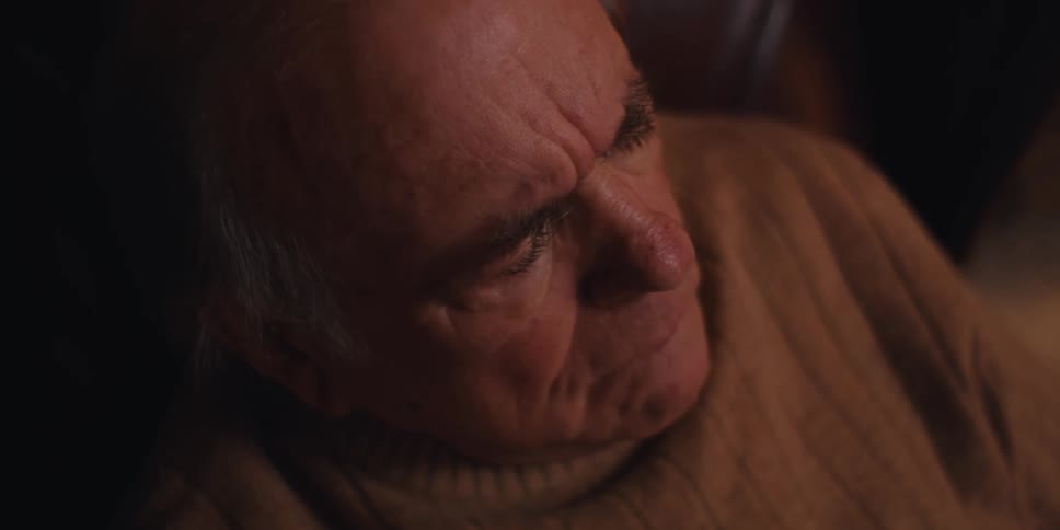 Elderly man sitting at home smiles at first at what he is reading before staring into space somewhat upset