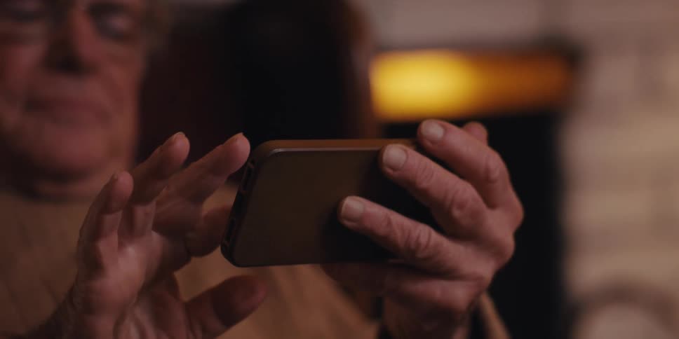 Elderly man sitting swiping on a smartphone