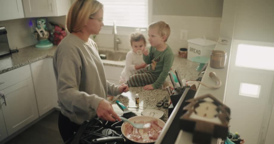 Mother cooking and paying attention to her two young children next door