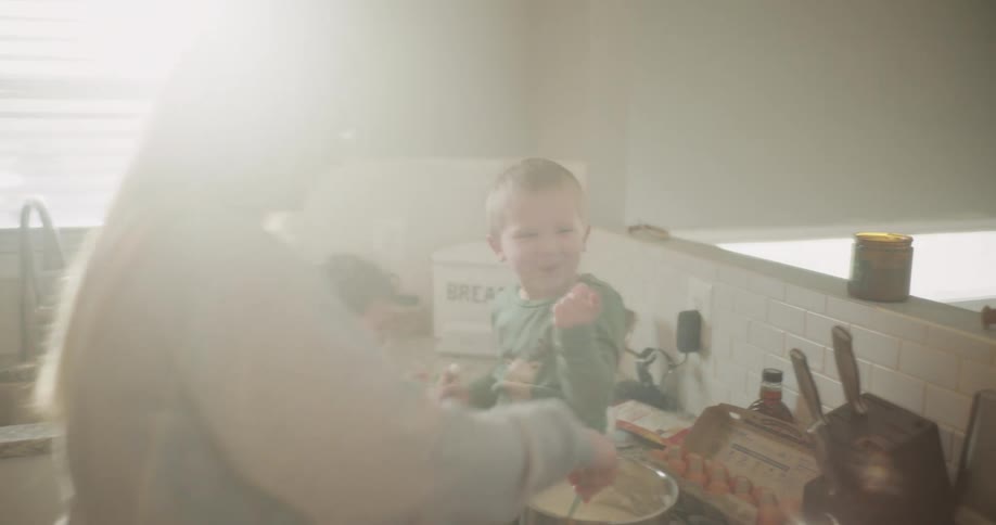 A mother and her children are preparing food on the kitchen counter in the morning