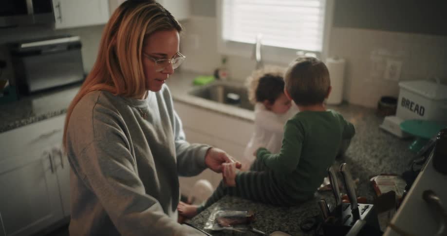 Mother frying bacon in a pan next to her two young children
